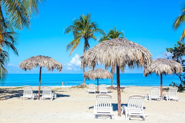 На Кубу в Варадеро _sun-loungers-umbrellas-sandy-beach-with-palms-by-sea-sky